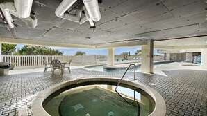 A pool area with a hot tub, lounge chairs, and a view of the surrounding landscape.