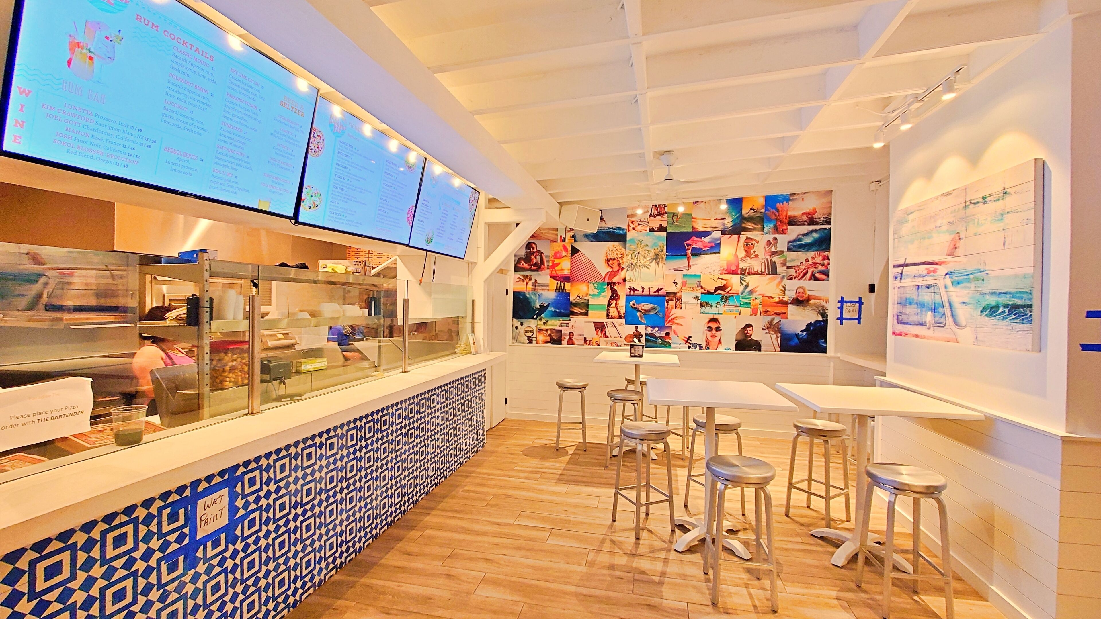 A restaurant interior with a counter, menu boards, and a wall of photos.