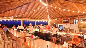 Eine Außenbar mit Holztischen und -stühlen, einer Bar und Blick auf den Nachthimmel.