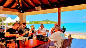 Ein Restaurant direkt am Strand mit Außenbereich, Bar und Blick auf die Küste.