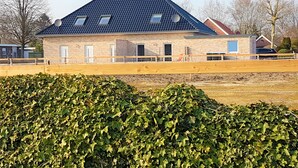 Een tweelaags bakstenen gebouw met een donker dak, schotels en een omheind gebied met houten palen.