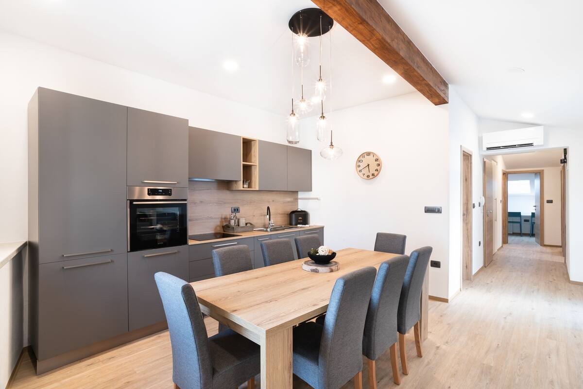 A modern kitchen with grey cabinets, a wooden dining table, and blue chairs.