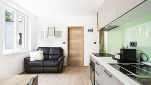 Una cocina moderna con encimera negra, puerta de madera y sofá de cuero negro.