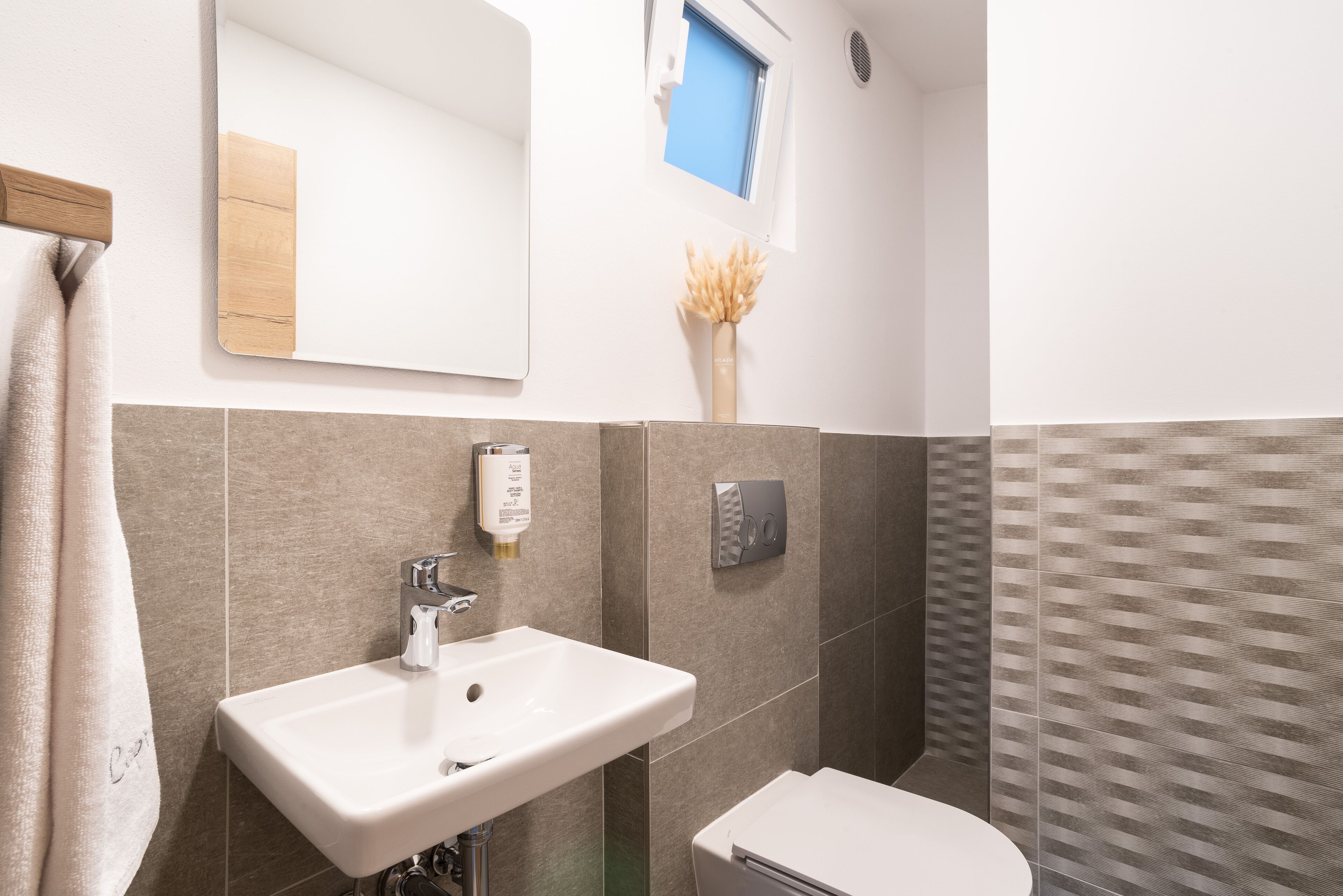 A bathroom with a white sink, a toilet, and a mirror.