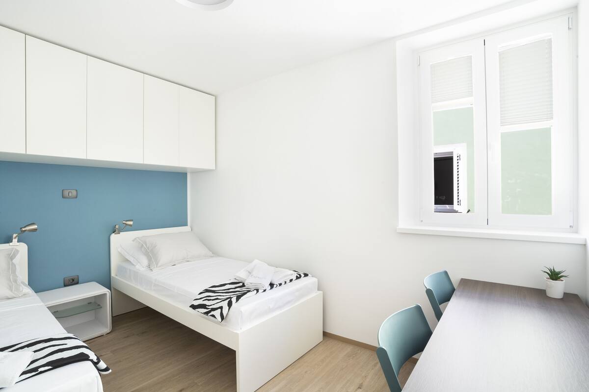 A bedroom with a bed, bedside table, and a window.