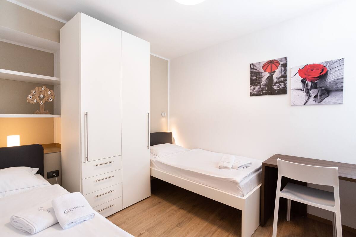 A bedroom with a bed, a desk, and a wardrobe.