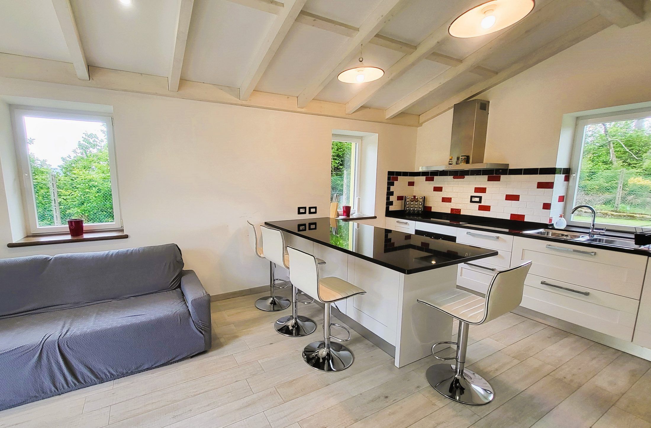 Una cucina moderna con isola centrale, sgabelli da bar e un divano grigio.