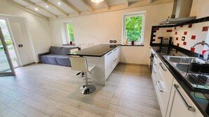 A modern kitchen with a central island, white cabinetry, and a black countertop. - Rosalba, Private solar heated pool, walk restaurants, romantic, mountain views.  (Corfino)
