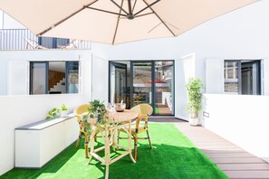 An outdoor patio with a table, chairs, and a large umbrella. - Heroismo Duplex Terrace (Porto)