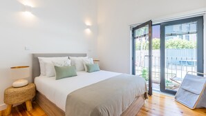 Een slaapkamer met een bed, een bedlampje en uitzicht op het omliggende landschap door een schuifdeur.