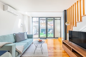 Relax in this stylish living room with a sofa, coffee table, and flat-screen TV, leading to a patio with a neighborhood view.