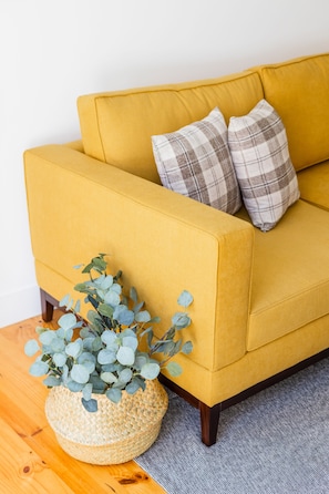 Relax on a modern sofa with plaid pillows and a natural touch from a woven basket with a plant.
