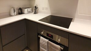 A modern kitchen with a built-in stove, oven, and stainless steel hood. - Stylish 2-bed Apartment in Manchester City Center (Manchester)