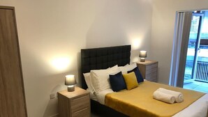 A bedroom with a bed, nightstands, a drawer, and a view of the outside. - Stylish 2-bed Apartment in Manchester City Center (Manchester)