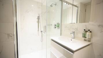 A modern bathroom with a glass-enclosed shower, a white sink, and a large mirror above the vanity.
