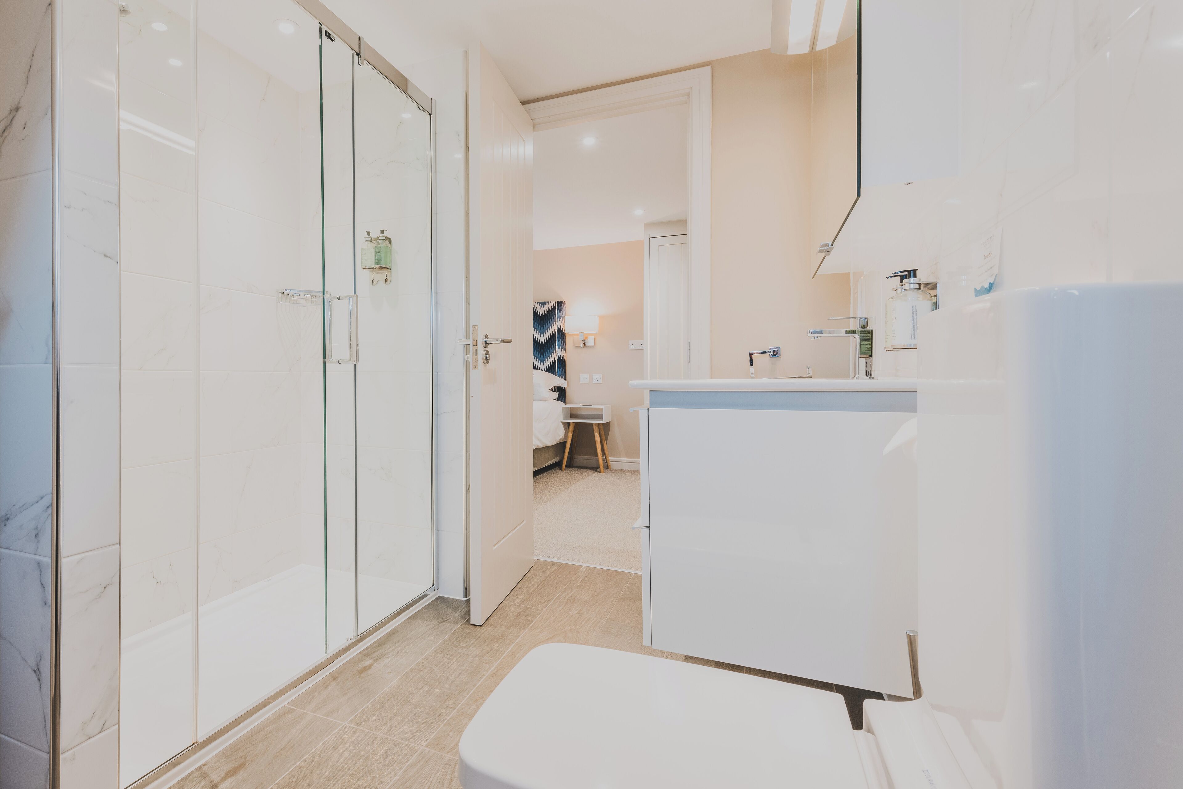 A modern bathroom with a glass shower enclosure, a white sink, and a mirror above it.
