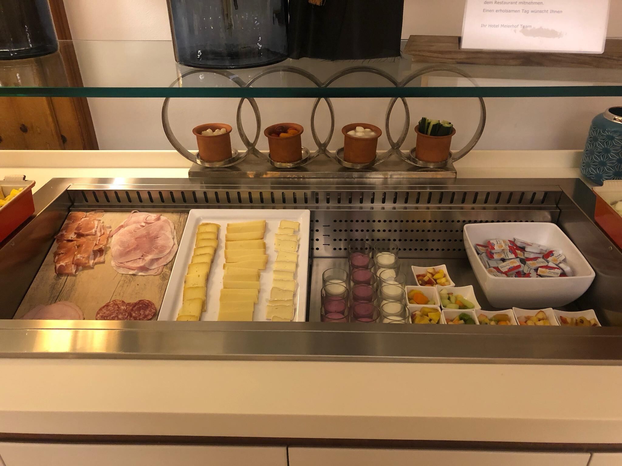 Uma área de buffet com diversos alimentos, incluindo carnes, queijos e frutas.