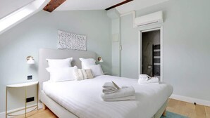 Une chambre à coucher comprenant un lit, une table de chevet, une œuvre d’art accrochée au mur et une armoire.