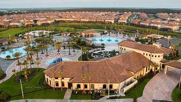 Un resort con varias edificaciones, un área de piscina central y jardines ajardinados.