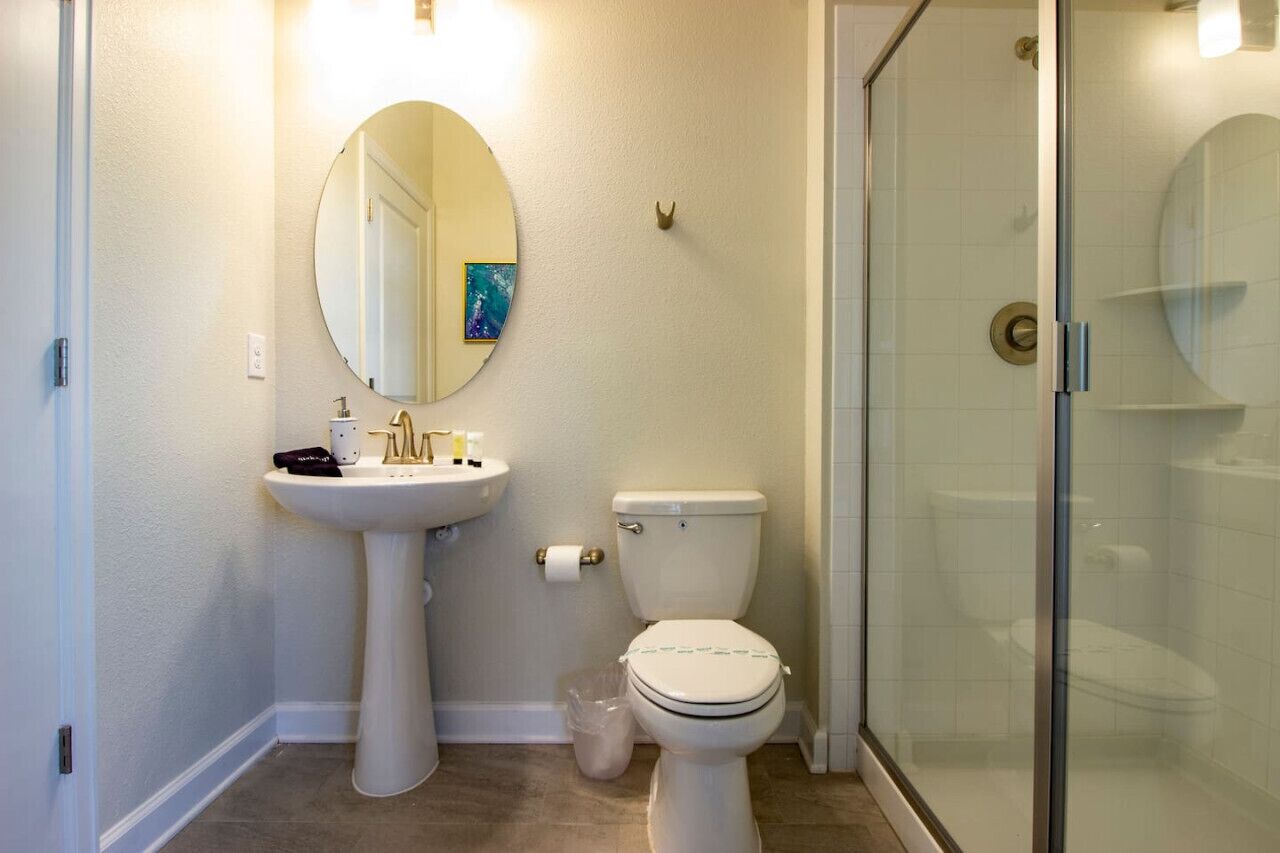 Une salle de bain avec un lavabo sur colonne, des toilettes et une douche à parois de verre.