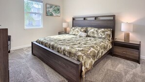 Un dormitorio con cama, mesitas de noche, ventilador de techo y ventana con persianas.