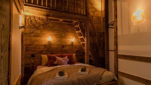 Una habitación acogedora de madera con una cama, una escalera y luces fijadas a la pared.