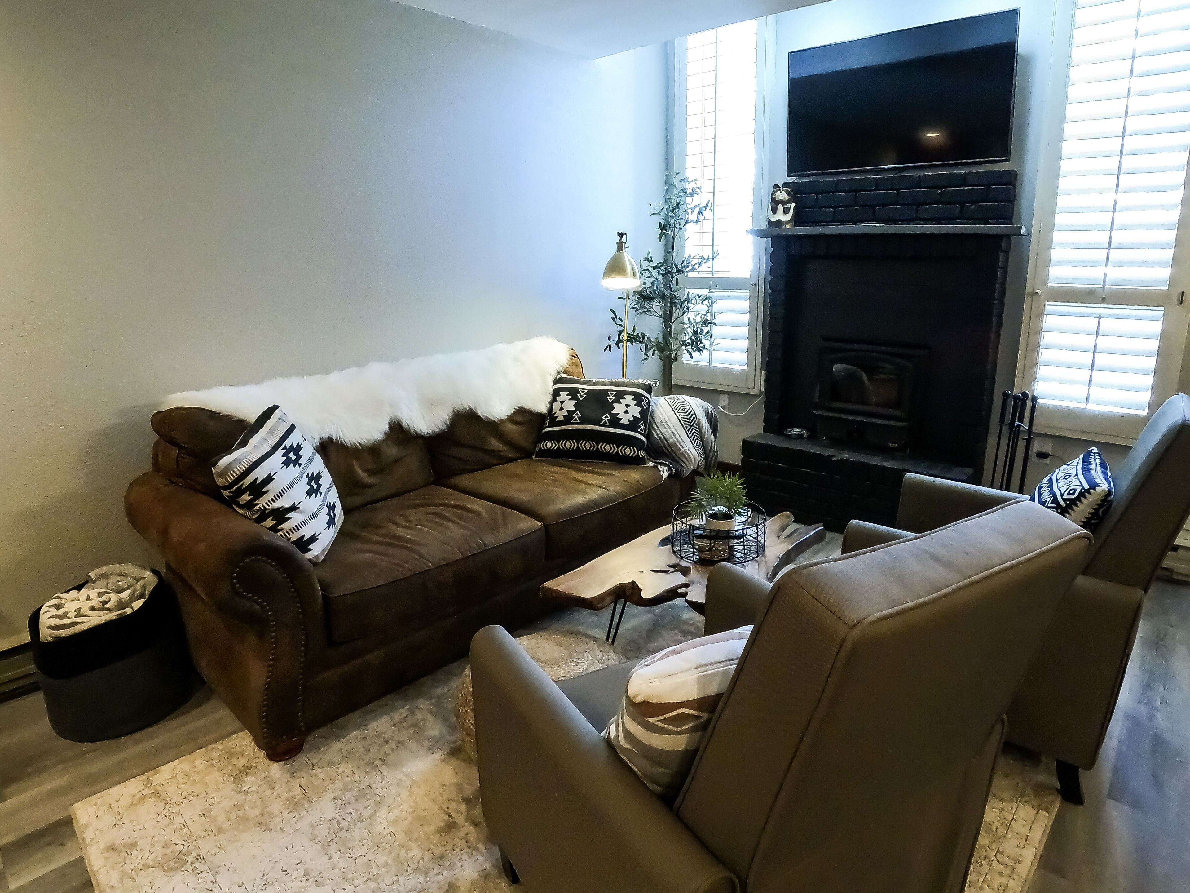 A living room with a brown leather sofa, two armchairs, a coffee table, and a fireplace.