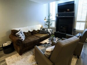A living room with a brown leather sofa, two armchairs, a coffee table, and a fireplace. - Incredible View! Completely Remodeled! Heated Pool! 2 Miles to Purgatory! (Durango)