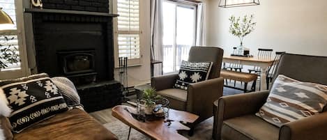 A cozy living room with a fireplace, comfortable seating, and a dining area.