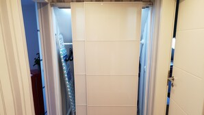 Un dressing accessible sans porte, doté de portes coulissantes, d’un plancher en bois et d’un distributeur d’eau visible.