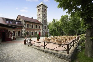 A courtyard with stone buildings, a tower, and outdoor seating. - SCHÖNECK VACATION APARTMENT (Bischofswerda)