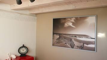 Una habitación con techo de madera, un armario rojo, un reloj en la pared y una fotografía enmarcada de una playa.