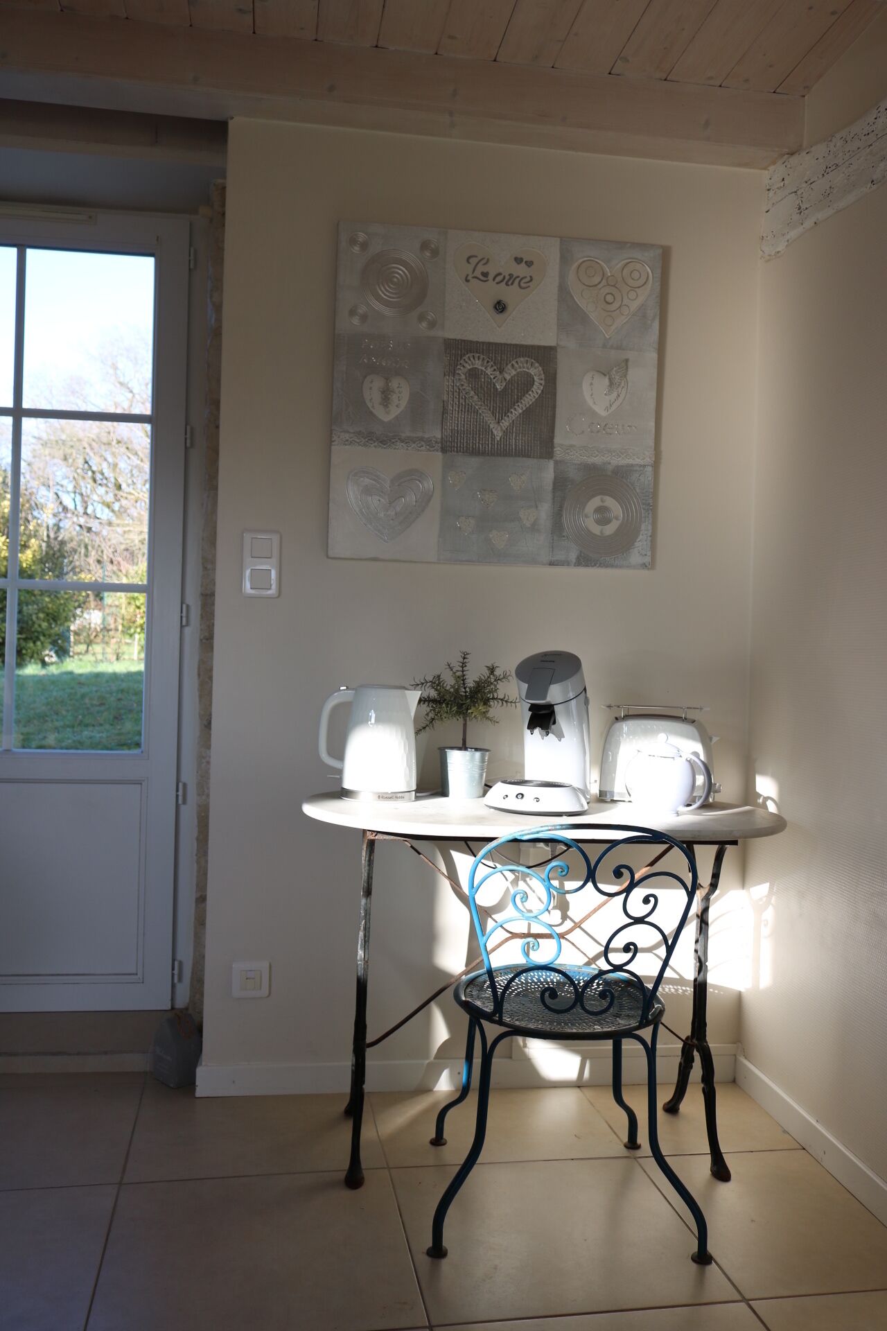 Un petit coin repas comprenant une table, une chaise, une machine à café, un grille-pain et un élément décoratif mural.