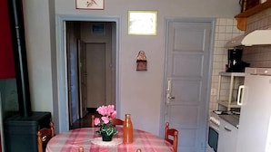 A dining area with a checkered floor, a table with a plaid tablecloth, and chairs. There is a stove and a refrigerator in the kitchen area. - Country house 5 min from lake genin (Charix)
