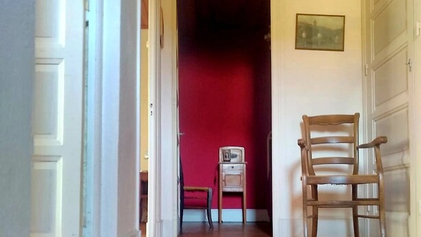 A hallway with wooden flooring, a red door at the end, and a wooden chair in the foreground. - Country house 5 min from lake genin (Charix)