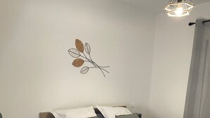 A neatly arranged bedroom with a bed, bedside tables, a lamp, and a wall decoration. - Superb T3 N°1 Garden level Apartment, swimming pool, terrace (bastia)