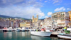 A marina with boats docked, a prominent church with two towers, and colorful buildings lining the waterfront. - Superb T3 N°1 Garden level Apartment, swimming pool, terrace (bastia)