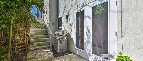 A patio with a barbecue grill, a wooden fence, and a welcome mat.