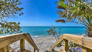 A wooden deck leading to a beach with clear blue water and a palm tree. - Waterfront-20 Steps to Private Beach-1+ BR-Pets OK-Kayaks-SUPs-Best Sharkteeth (Englewood)