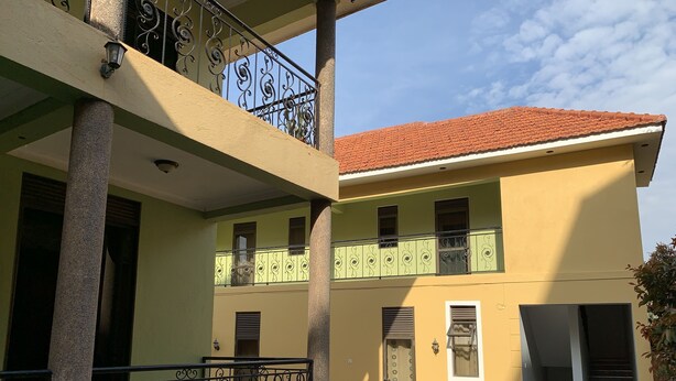 Ein zweistöckiges Gebäude mit einem Ziegeldach, einem Balkon mit schmiedeeisernen Geländern und einem gepflasterten Innenhof.