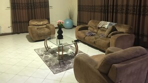 Ein Wohnzimmer mit zwei braunen Sofas, einem Glastisch und einem blauen Gymnastikball.