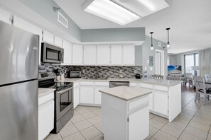 A modern kitchen with a central island, stainless steel appliances, and a tiled backsplash.
