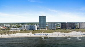 Un paysage urbain côtier avec de hauts immeubles, une plage avec des transats et un ciel dégagé.