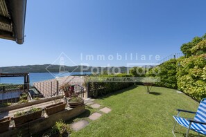 A patio with a view of the sea, a garden with stepping stones, and a blue chair.