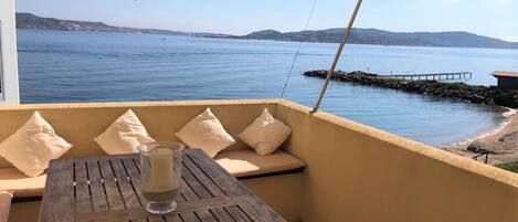 A wooden table with a glass of water, beige cushions, and a hanging lantern.