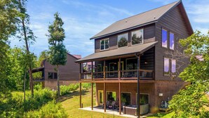 Ein zweistöckiges Holzhaus mit Balkon, Whirlpool und überdachter Terrasse.