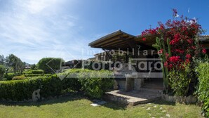 A property with a covered patio, a stone pathway, and a well-maintained garden with hedges and flowering plants. - 13A Appartamento - 13A PORTO MANNU (Palau)