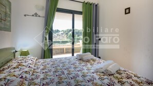 A bedroom with a bed, a nightstand, a window with curtains, and a view of a mountainous landscape. - 18BAIADELFARO - 18 BAIA DEL FARO (Palau)