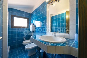 A bathroom with blue tiles, a white sink, and a toilet. - 18BAIADELFARO - 18 BAIA DEL FARO (Palau)