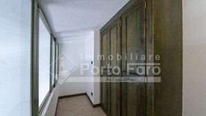 A hallway with a tiled floor, a large wooden door, and a window on the left. - 18BAIADELFARO - 18 BAIA DEL FARO (Palau)
